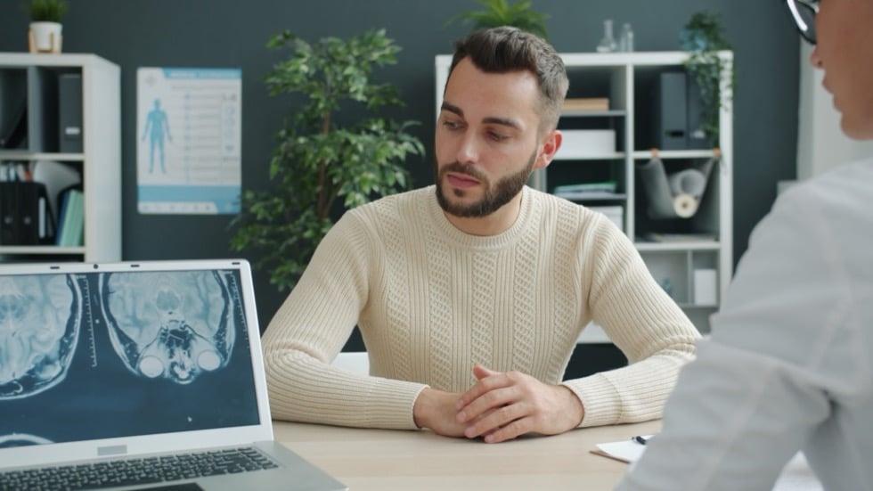 A patient sitting down with their clinician at the start of a consult