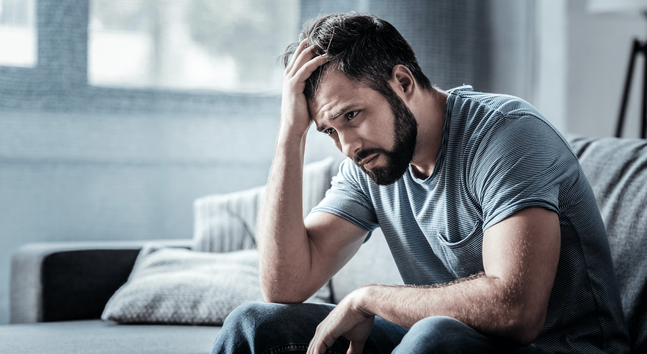 Man looks stressed and upset holding his head in his hand