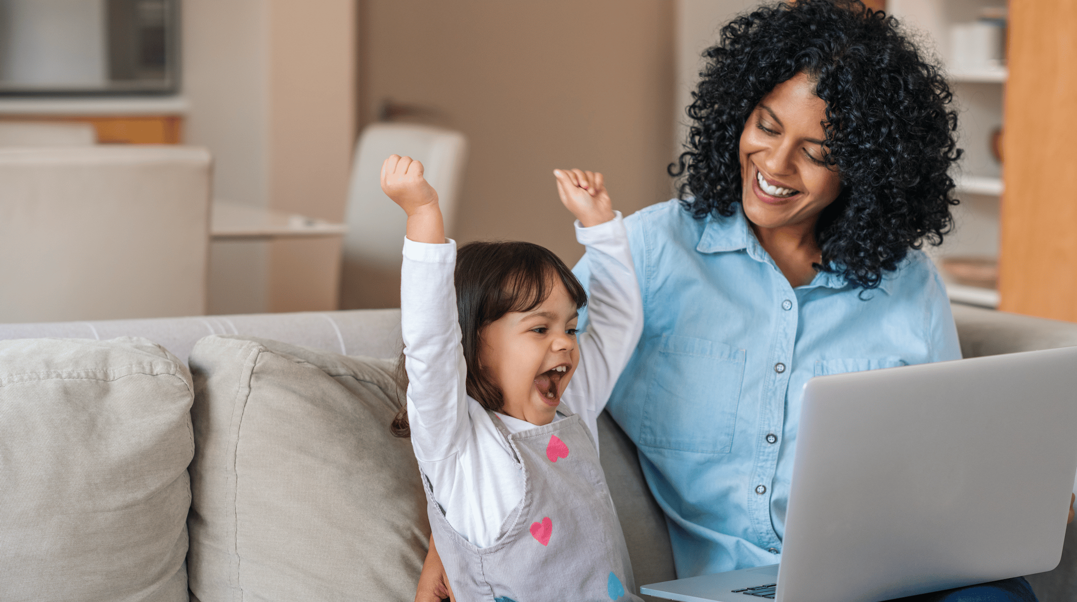 Young girl sitting on the couch with her mother on the computer